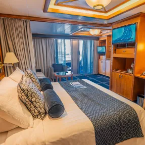 Luxury Cruise Ship Cabin with Ocean View An elegantly appointed cruise ship stateroom featuring a king bed with decorative pillows