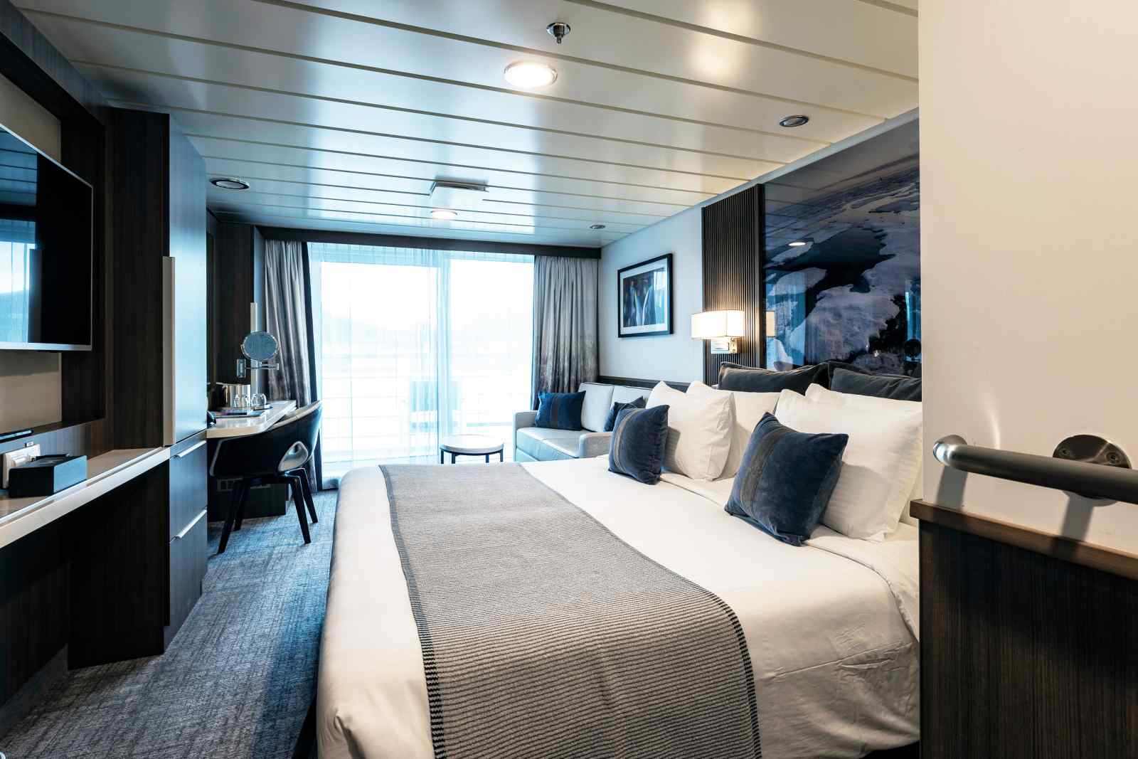 Luxury cruise ship stateroom with ocean view, featuring modern furnishings and comfortable bedding.
