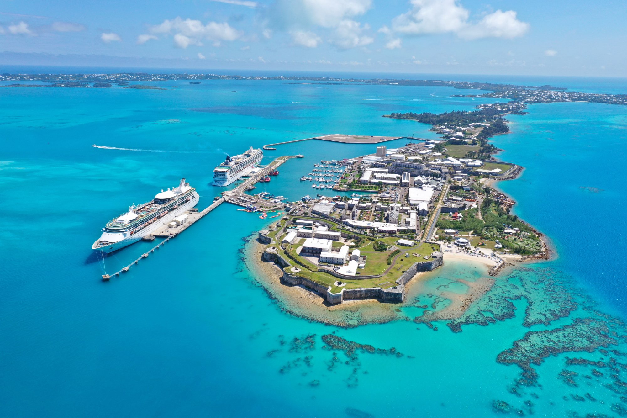 adobestock-778287167 An aerial view of a large cruise ship docked at King's Wharf in Bermuda, showcasing the iconic fortress and colonial architecture of the island alongside turquoise waters.