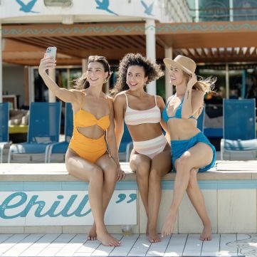 Poolside Selfie at Margaritaville at Sea Three young women in colorful swimwear take a selfie together at the pool deck of Margaritaville